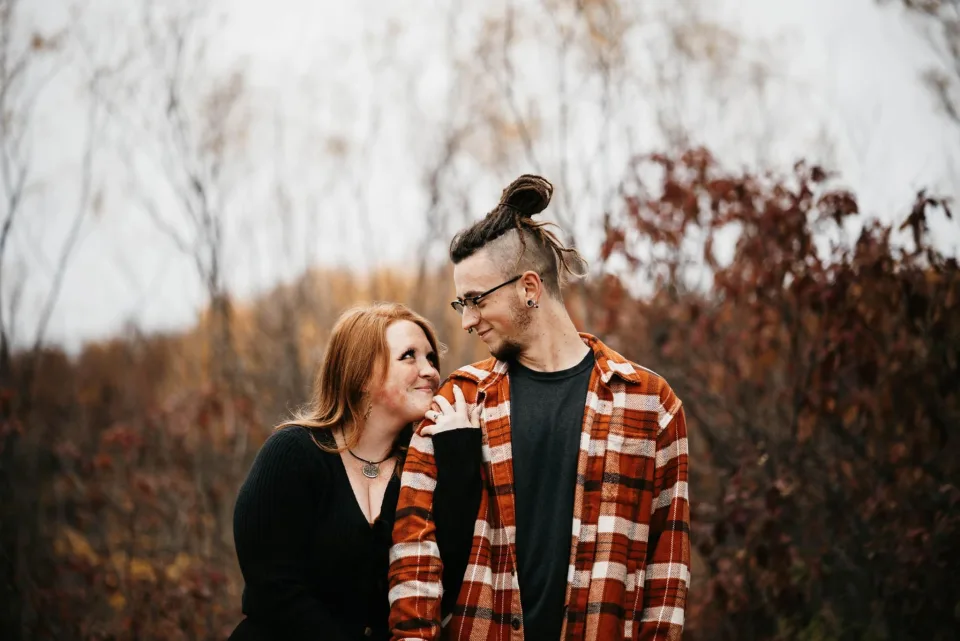 Autumn and Grayson smiling at one another in an autumn field