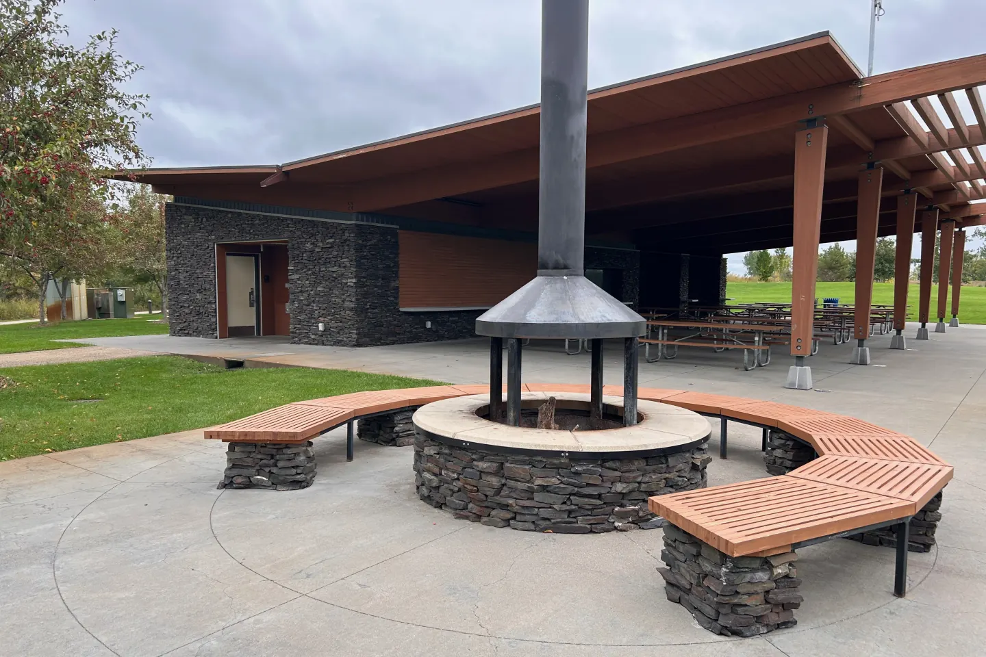 The stone fire circle and curved benches beside the covered pavilion