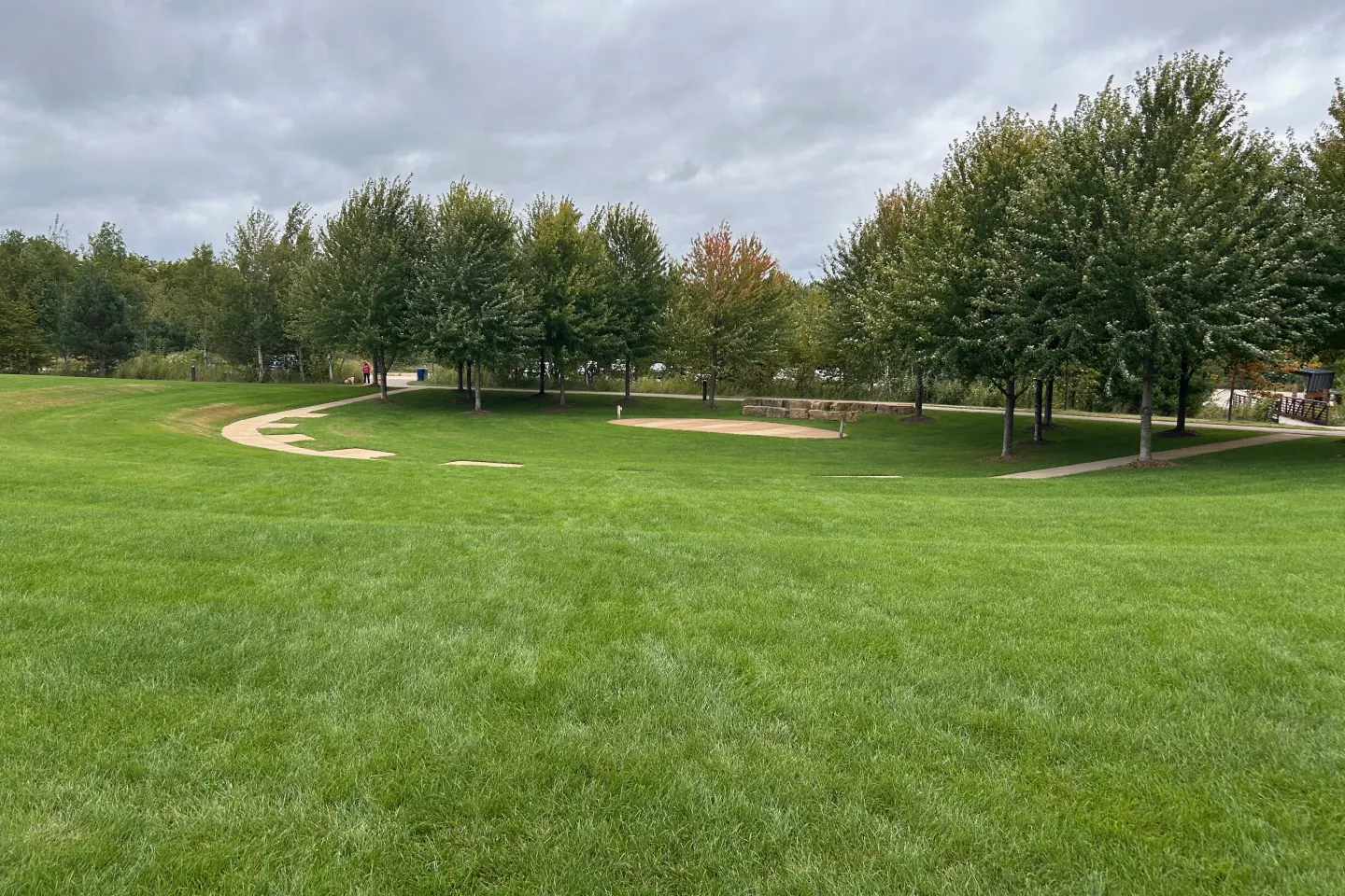 The broad grassy rehearsal area surrounded by trees and walking paths