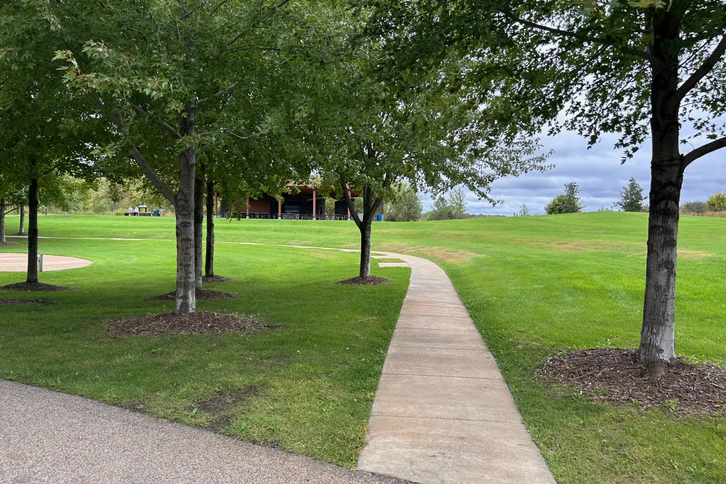A curving path through the lawn and trees leading toward the shelter